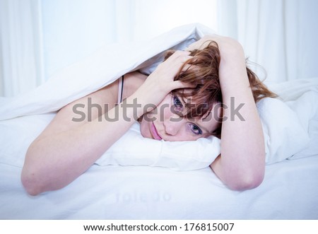 woman with red hair in her bed with insomnia and can\'t sleep on a white background