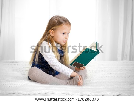 scared cute blonde haired school girl wearing a school uniform reading a book sitting on the bed