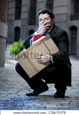 frustrated business man fired in crisis carrying cardboard box on street