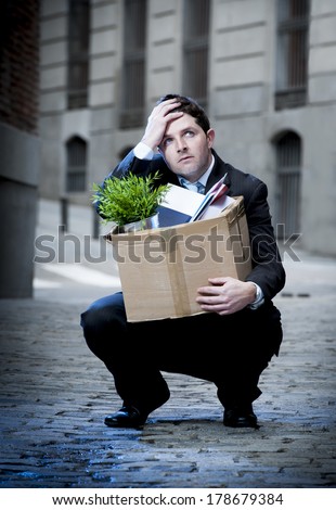 frustrated business man fired in crisis carrying cardboard box on street