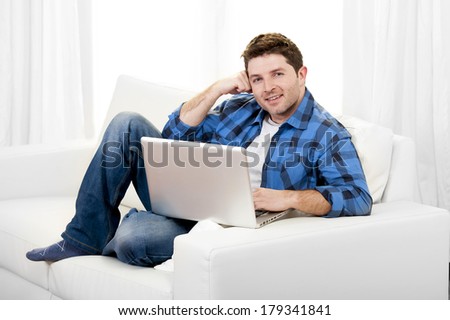 Young attractive relaxed man in casual clothes working with Computer  sitting on couch or sofa at home
