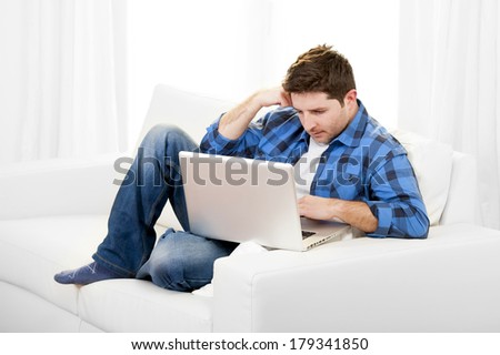 Young attractive relaxed man in casual clothes working with Computer  sitting on couch or sofa at home