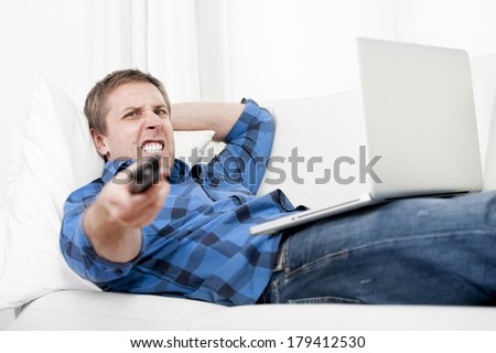 attractive angry student with Computer at home switching tv on
