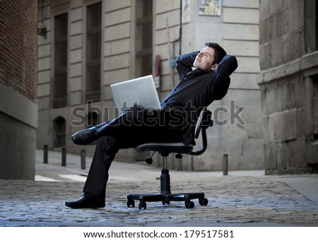 Happy relaxed Business Man sitting on Office Chair on Street with Computer