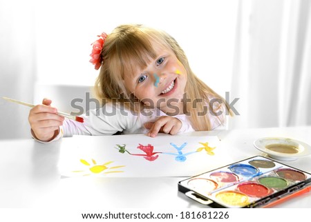 Cute artistic little blonde girl painting and drawing family in colors
