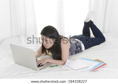 young beautiful asian chinese student or business woman at home lying on bed in casual clothes studying and working with computer and notepads in stress before exam