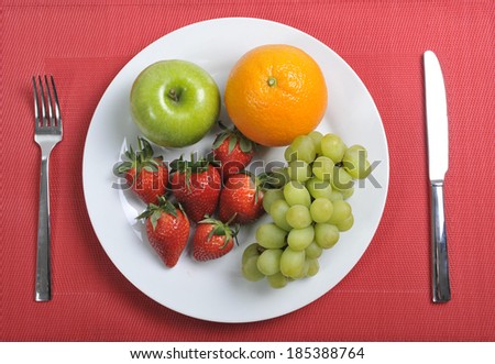 plate with mixed fruits in healthy nutrition concept on red mat