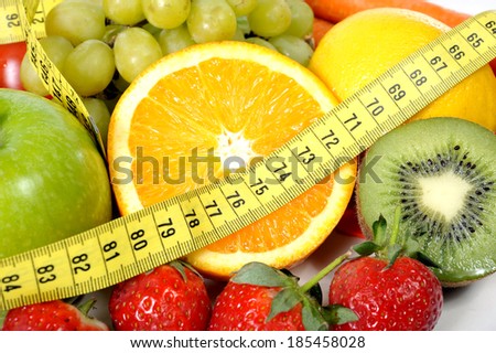 macro vegetables as tomatoes and carrots with fruit as grapes and apple wrapped in measure tape in diet , weight loss and healthy nutrition concept isolated on white background