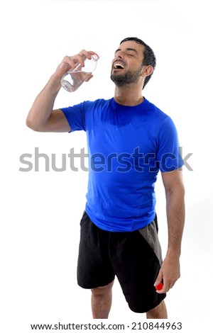 young attractive and athletic sport man all wet smiling happy and drinking water bottle after training  isolated on white background