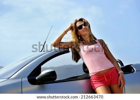 young sexy chic woman with sunglasses leaning on cabrio sport car in relax on the beach summer holidays having a sunbath in front of the sea