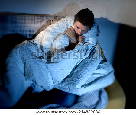 young sick looking man sitting on couch at home in scary and desperate looking suffering insomnia, depression, nightmares, emotional crisis or mental disorder with dim light