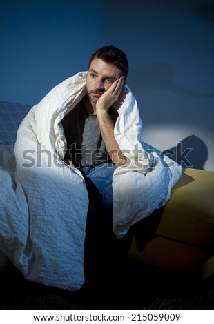 young sick man sitting on couch at home scary and desperate suffering insomnia, depression, nightmares, emotional crisis, mental disorder with a dim light and deep dark shadows