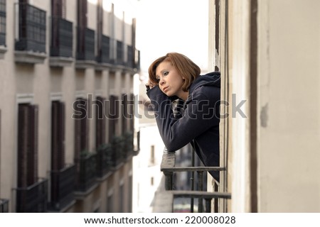 young attractive woman suffering depression and stress at the home balcony window terrace in pain and grief feeling sad and desperate in city urban background