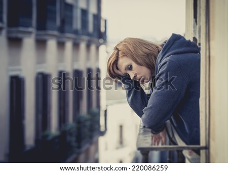 young attractive woman suffering depression and crying in stress outdoors at home balcony terrace window in pain and grief feeling sad and desperate in urban background