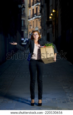 young attractive jobless business woman depressed and fired from work carrying cardboard box office belongings wasted on street after loosing her job, worried and sad