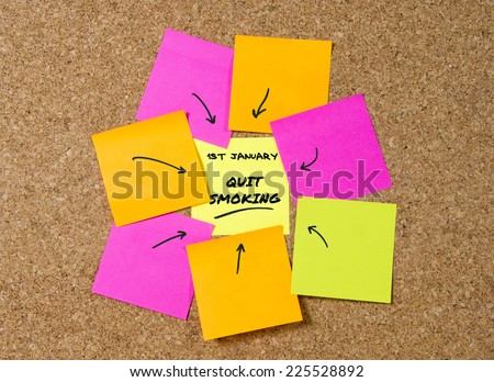 yellow post it note on cork board and marker arrow as reminder of quit smoking, stop cigarettes, nicotine and tobacco habit New Year resolution and start healthy life concept
