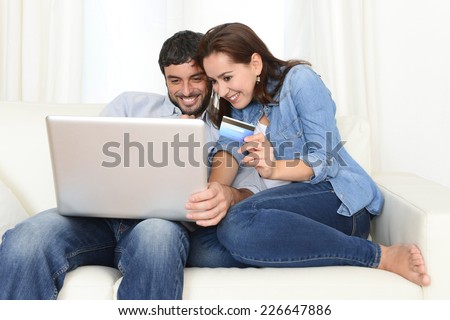 young attractive and nice happy couple online shopping with credit card and computer laptop sitting on couch at home in internet commerce and banking concept