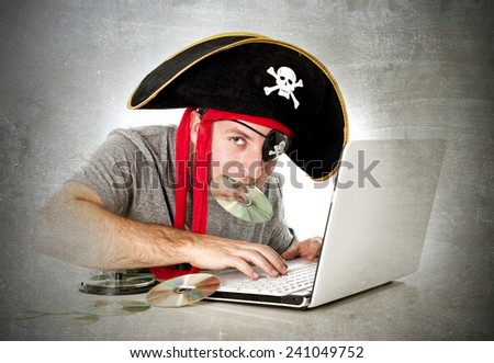 man dressed as pirate with CD in his mouth at computer laptop downloading music files and movies in copyright violation and illegal internet piracy concept