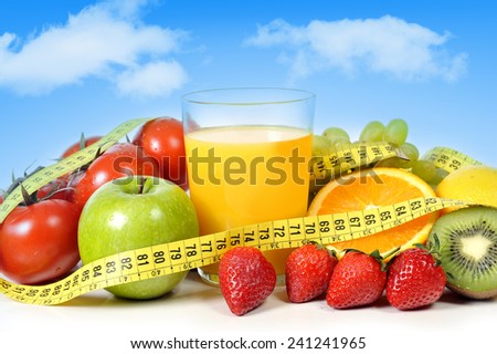 mix of fresh fruit as apple , grapes, strawberries, kiwi and vegetables as tomato with  glass of orange juice all wrapped in measure tape on a blue sky background in healthy nutrition and diet concept