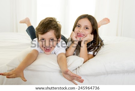 Brazilian 7 years old little girl playing on bed or couch together with her 4 years old small brother smiling happy in brotherhood and children lifestyle concept