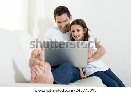 young attractive father sitting on couch with 7 years old sweet little girl daughter using computer laptop at home smiling happy together in children technology concept