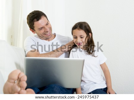 young attractive father sitting on couch with 7 years old sweet little girl daughter using computer laptop at home smiling happy together in children technology concept