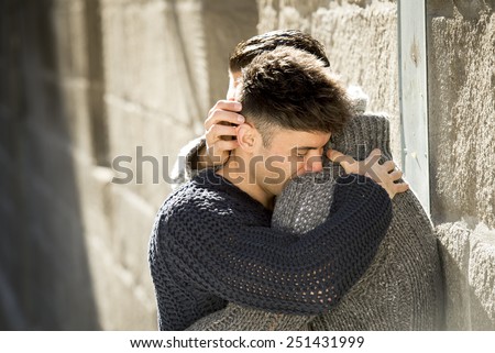 young happy attractive gay men couple holding , hugging and kissing each other outdoors on street in free homosexual love concept in urban background