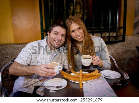 young beautiful American tourist couple having spanish typical breakfast hot chocolate with churros smiling happy in tourism and holidays travel in Europe concept