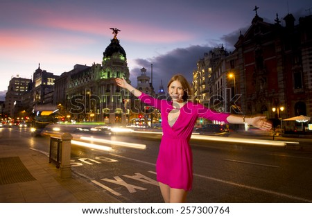 young happy attractive woman spreading arms posing at night in Madrid city having fun in town on summer evening wearing glamour dress in female fashion concept