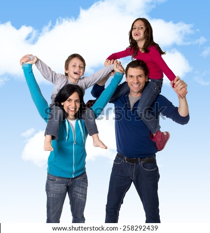 young happy Brazilian mother and father playing with little son and daughter having fun all together outdoors on a blue sky with clouds in family love and new generation concept