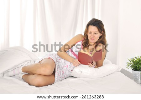 young attractive and sexy student woman lying on bed reading novel or studying book posing happy and relaxed at home bedroom