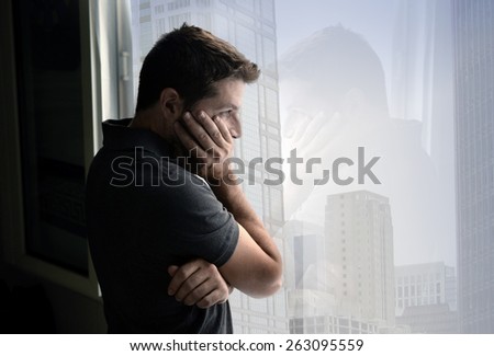 young attractive man leaning desperate on window glass at business district home, looking worried, depressed, thoughtful and lonely suffering depression in work or personal problems