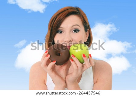 young attractive read hair woman holding green apple and chocolate donut cake  outdoors  in fitness, diet and healthy nutrition concept in health and natural food versus junk and sweet