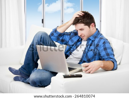 Young attractive man relaxed on couch at living room wearing casual clothes using computer laptop looking happy and satisfied surfing on internet or freelance working from home