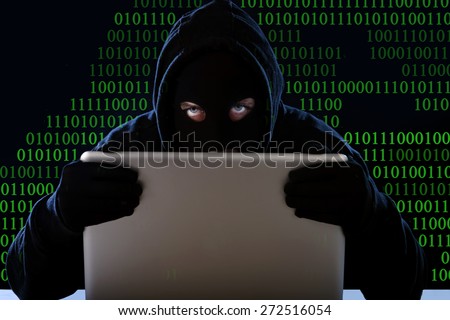 hacker man in black hood and mask with computer laptop in dangerous dark look hacking system having access to data info and privacy in business digital intruder and cyber crime concept