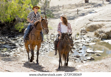 young American Australian man as father or horse instructor of young girl or  teen daughter riding little pony wearing cowgirl hat in countryside Summer vacation ride