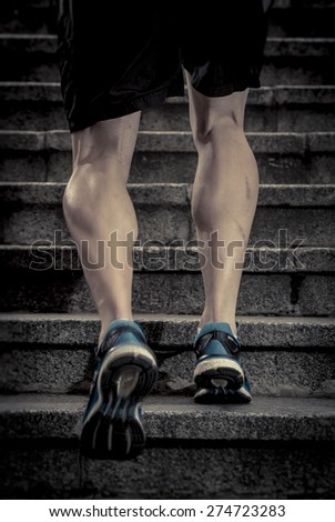 athletic legs of young sport man with sharp scarf muscles running on staircase steps jogging in urban training workout or runner competition in fitness and healthy lifestyle concept