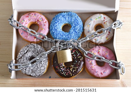 box full of tempting delicious donuts wrapped in metal chain and lock in sugar and sweet addiction and diet body and dental care concept
