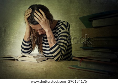 young stressed student girl studying pile of books on library desk preparing MBA test or exam in stress feeling tired and overwhelmed in youth education concept grunge messy background style