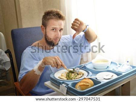 young man in hospital room after suffering accident eating the healthy diet clinic food in upset and moody face expression disliking the medical center meal