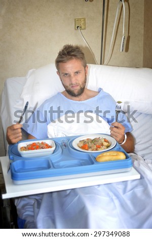 young man in hospital room after suffering accident eating healthy vegetables  as  diet clinic food in upset disgusting and moody face expression disliking the medical center meal