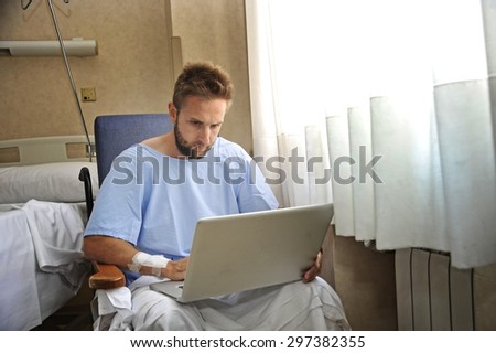 young man in hospital room sick and injured using internet in computer laptop feeling sad and depressed researching info on his own disease injury or sickness