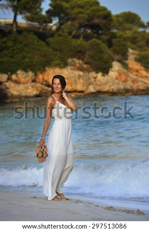 young attractive and beautiful woman enjoying vacation summer holidays at Spain coast village walking on beach sand letting white dress getting wet on sea water relaxed and happy