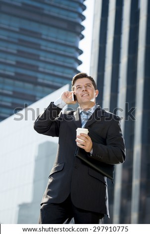 young attractive businessman in suit and necktie talking on mobile smart phone smiling happy and confident standing outdoors in exterior office buildings on business district in success concept