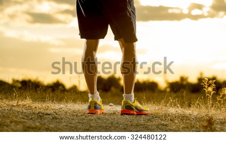 close up image of young man strong legs off trail running at amazing summer sunset in sport and healthy lifestyle concept and jogging cross country training workout