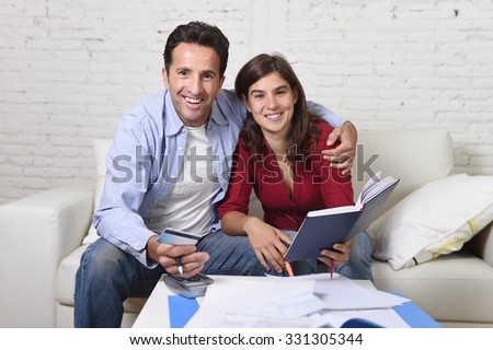 young attractive couple accounting at home couch with bank papers and documents, calculator and credit card living cost and mortgage expenses smiling happy in financial success and wealth