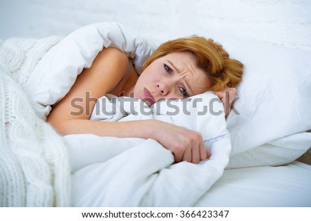 young attractive woman in sad and depressed face expression with eyes wide open lying in bed looking sick and unable to sleep suffering depression , nightmares or insomnia sleeping disorder