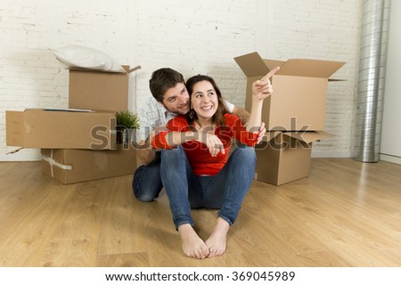 young happy married couple sitting on flat floor unpacking cardboard boxes moving in new home apartment smiling happy planning for decoration of the house in real estate concept