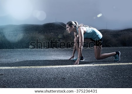 young attractive sport woman posing on start grid style ready for running workout on asphalt road in dramatic harsh light advertising style with lens flare in high performance and energy concept