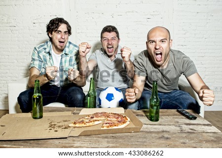 group of friends fanatic football fans watching soccer game on television celebrating goal on couch screaming excited and ecstatic in crazy happy face expression with beer and pizza